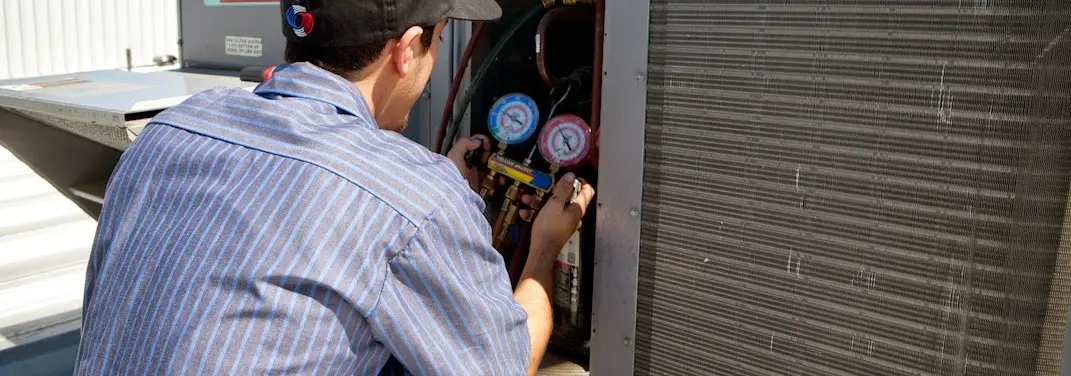 HVAC technician servicing a condenser unit in Pennfield